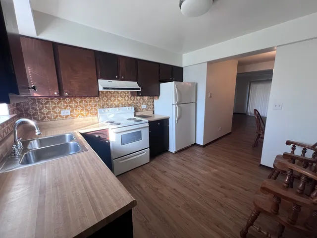 a kitchen with stainless steel appliances wooden floors wooden cabinets a sink and a stove