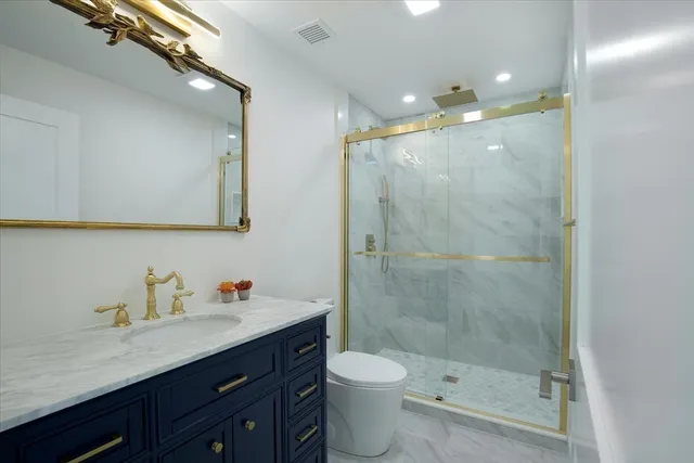a bathroom with a shower sink vanity mirror and toilet