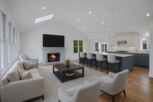 a living room with furniture a fireplace a flat screen tv and kitchen view