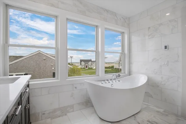 a bathroom with a sink a bathtub and next to a window
