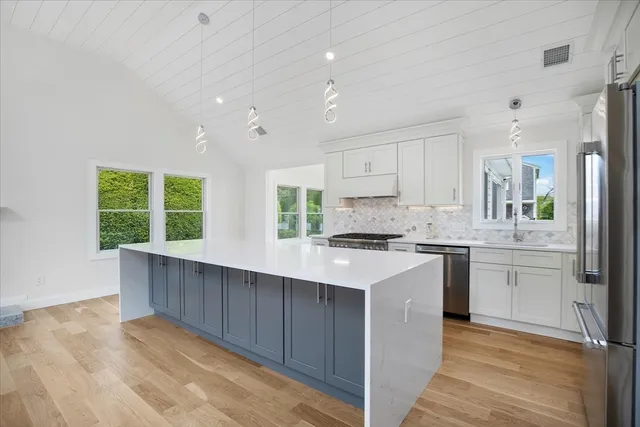 a kitchen with stainless steel appliances granite countertop a sink a stove a refrigerator cabinets and a large window