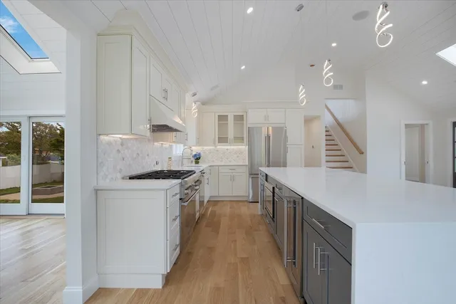 a kitchen with white cabinets appliances and wooden floor