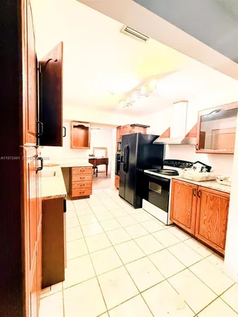 a living room with furniture a flat screen tv and a refrigerator