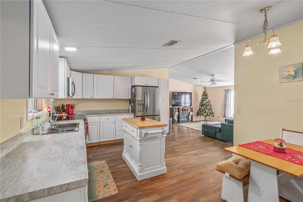 6601 Southwest 84th Street Ocala, FL 34476 - Photo 15 of 36 a kitchen with a refrigerator a stove top oven a sink dishwasher and white cabinets with wooden floor