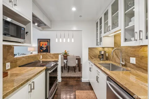 a large kitchen with granite countertop a sink and a stove top oven