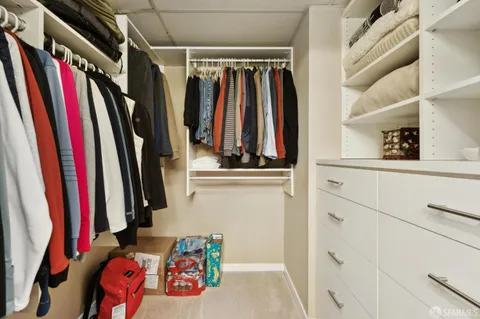 a view of walk in closet with clothes and shoes