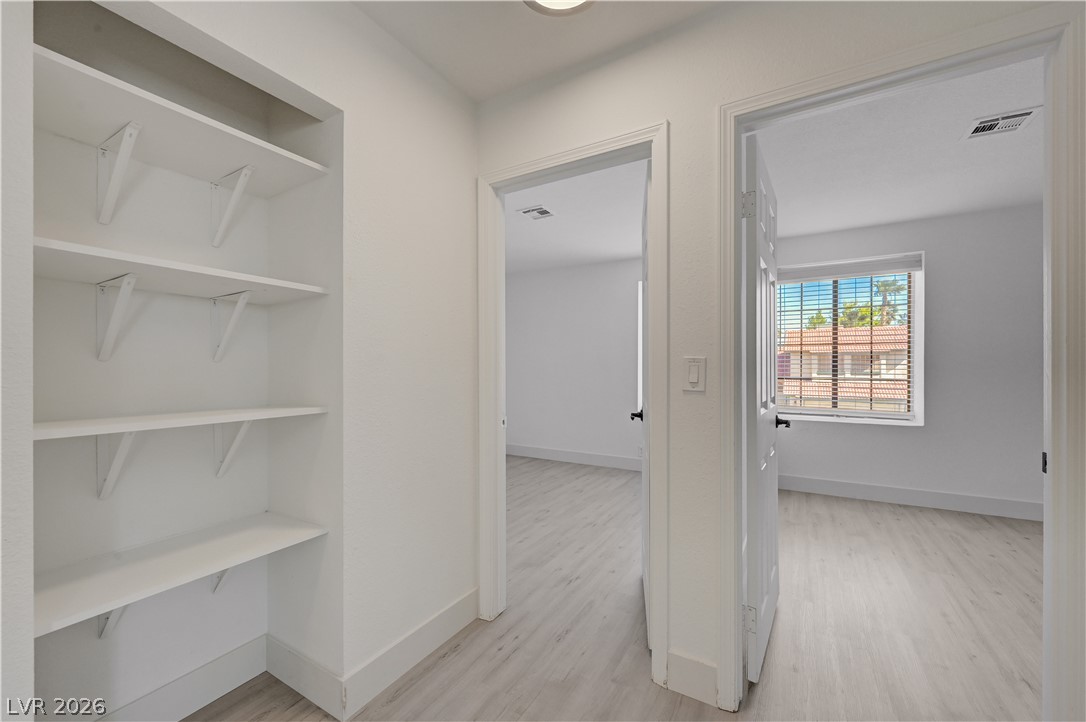 6505 Deadwood Road Las Vegas, NV 89108 - Photo 20 of 33 A well-lit hallway with built-in shelving connects two spacious, neutral-toned rooms.