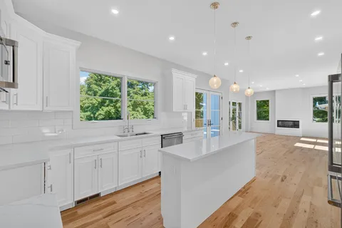 a large white kitchen with kitchen island granite countertop a large window