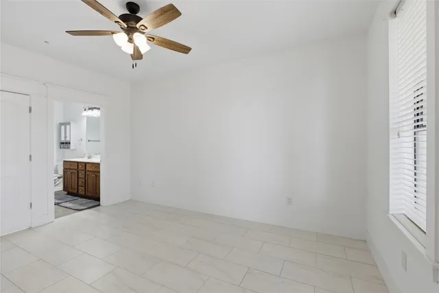 an empty room with windows and fan