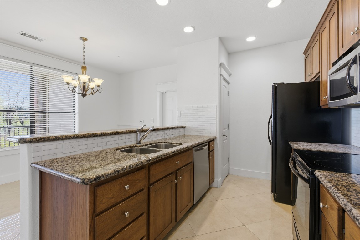17700 Edgewood Way, Unit 101 Jonestown, TX 78645 - Photo 9 of 40 a kitchen with stainless steel appliances granite countertop a sink and a refrigerator