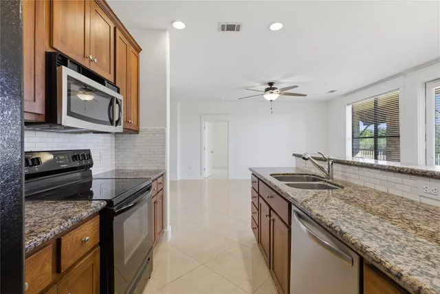 a kitchen with stainless steel appliances granite countertop a sink a stove and a wooden cabinets