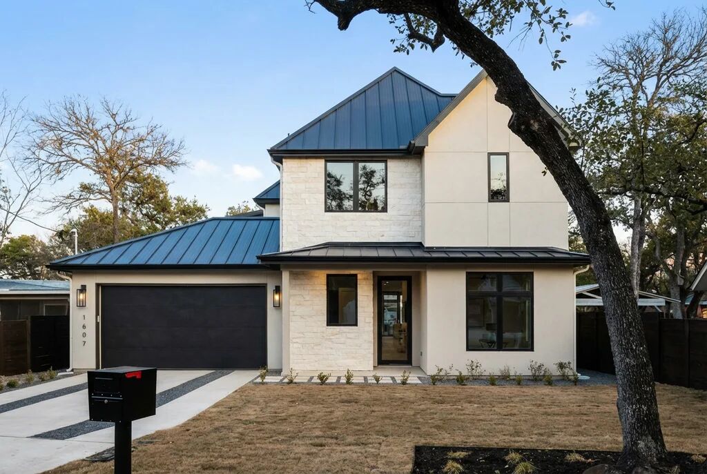 View of front of house with a standing seam roof, concrete driveway, an attached garage, and stucco siding