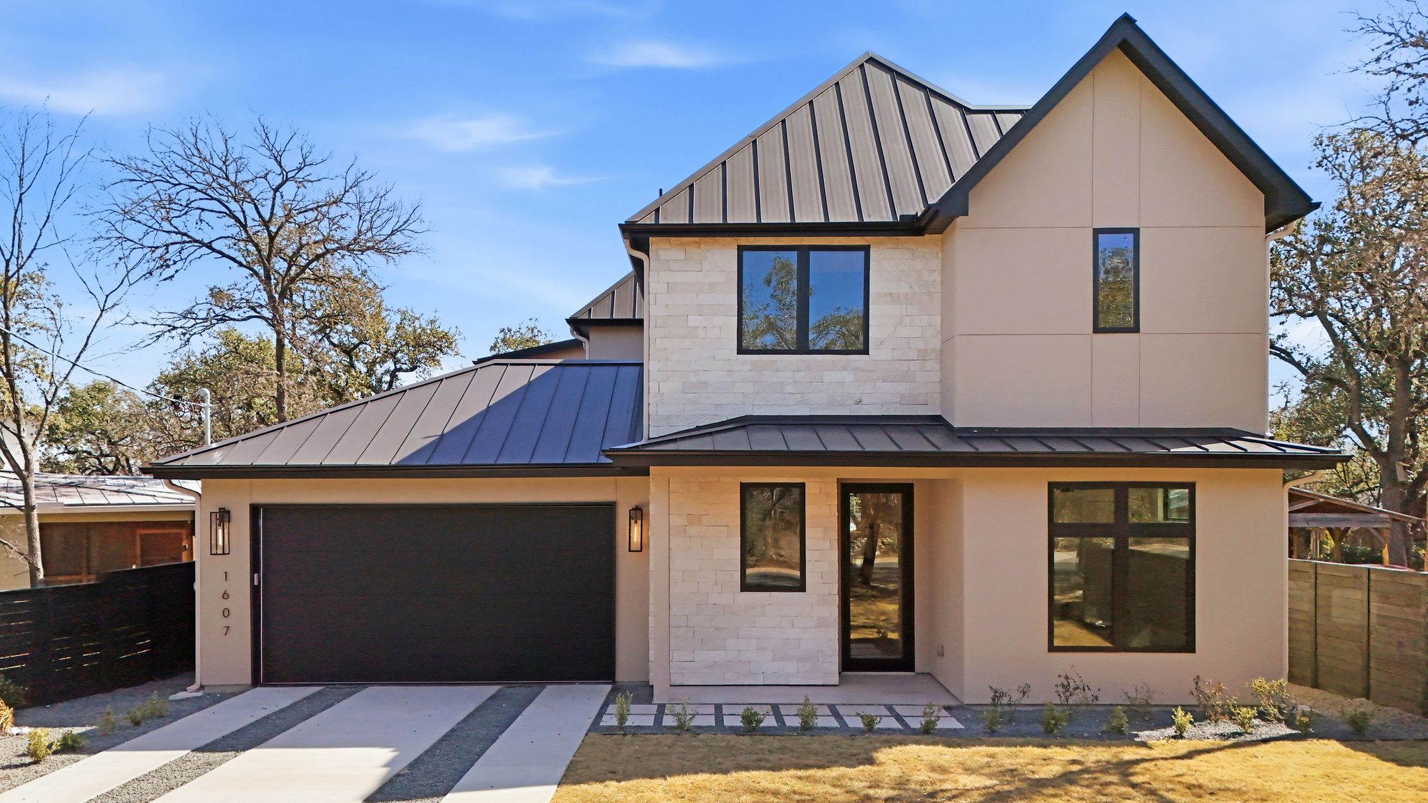 Modern home with a standing seam roof, concrete driveway, and a garage