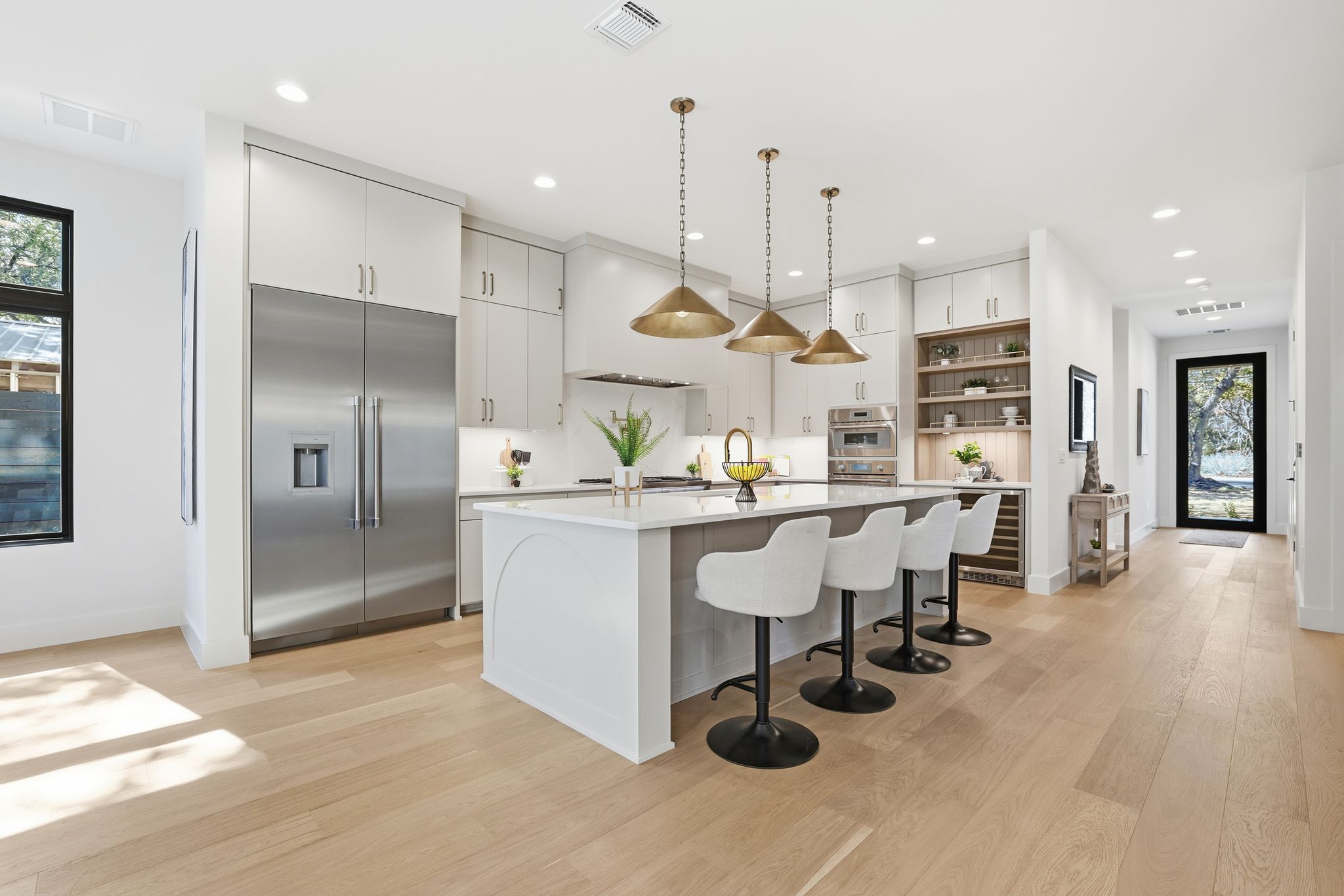 1607 Rabb Road Austin, TX 78704 - Photo 12 of 40 Kitchen with stainless steel appliances, a breakfast bar, pendant lighting, a center island with sink, and light wood-type flooring