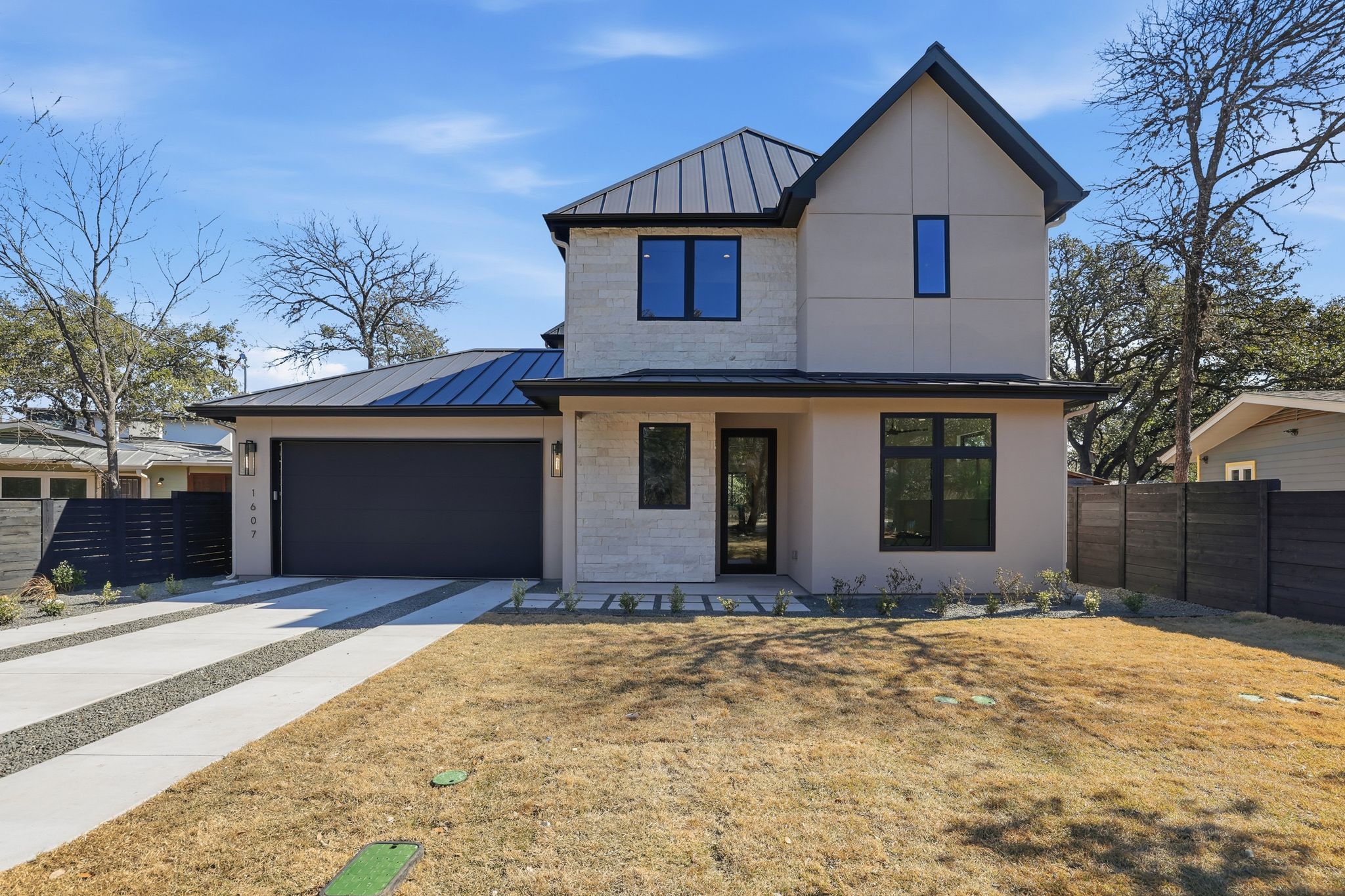 1607 Rabb Road Austin, TX 78704 - Photo 2 of 40 View of front of property featuring a standing seam roof, concrete driveway, covered porch, an attached garage, and stucco siding