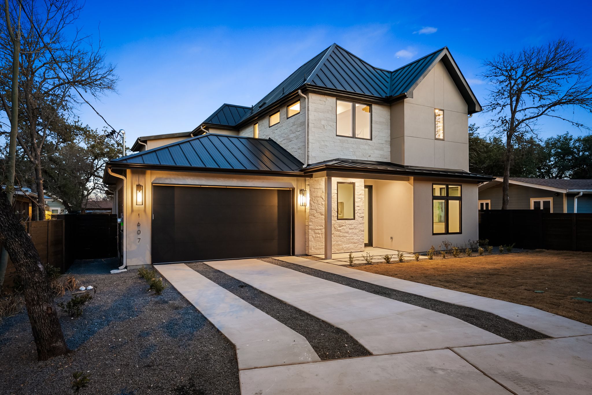 1607 Rabb Road Austin, TX 78704 - Photo 3 of 40 View of front facade with a standing seam roof, driveway, an attached garage, and stucco siding
