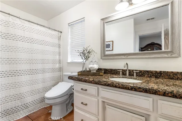 a bathroom with a granite countertop toilet sink and mirror