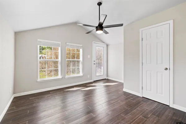 a view of an empty room with wooden floor and a window