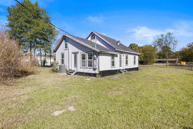 a view of a house with a big yard and large trees