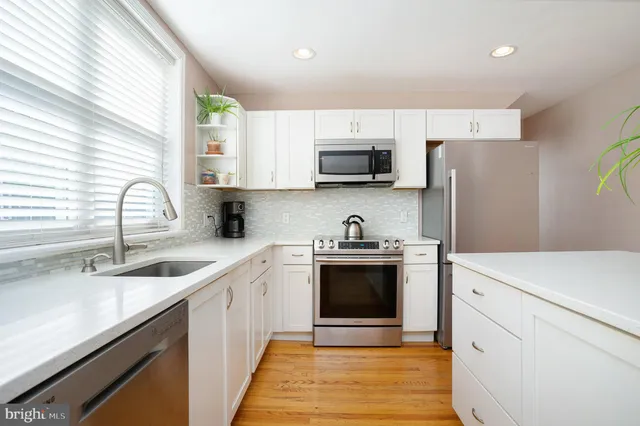 a kitchen with stainless steel appliances a sink cabinets and a window
