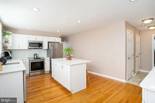 a large kitchen with a stove top oven a sink a counter space and wooden floor