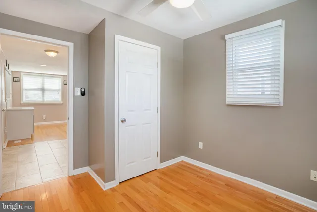 a view of empty room with wooden floor and fan