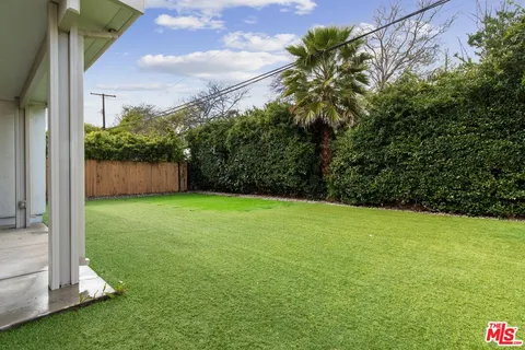 a view of a house with a yard potted plants and a tree