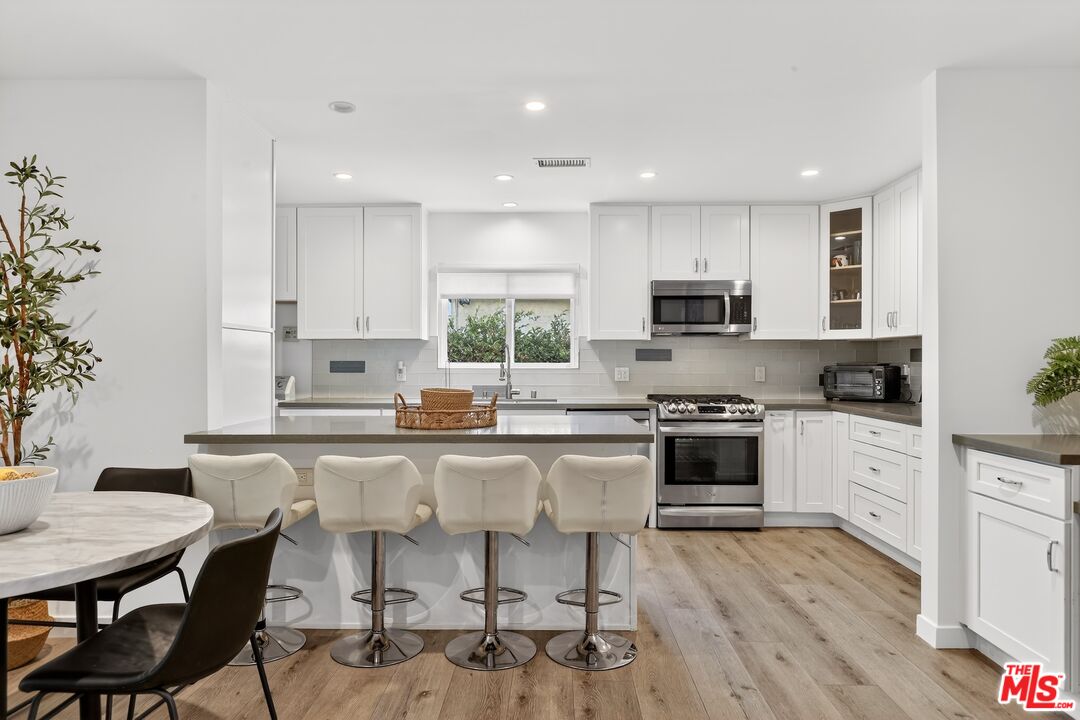 6565 Randi Avenue Woodland Hills, CA 91303 - Photo 6 of 25 a kitchen with a stove a sink a microwave a dining table and chairs