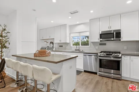 a kitchen with stainless steel appliances a stove a sink a microwave a refrigerator and cabinets