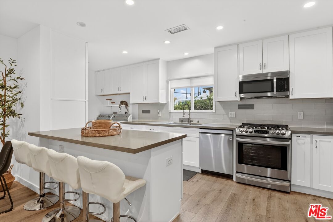 6565 Randi Avenue Woodland Hills, CA 91303 - Photo 7 of 25 a kitchen with stainless steel appliances a stove a sink a microwave a refrigerator and cabinets