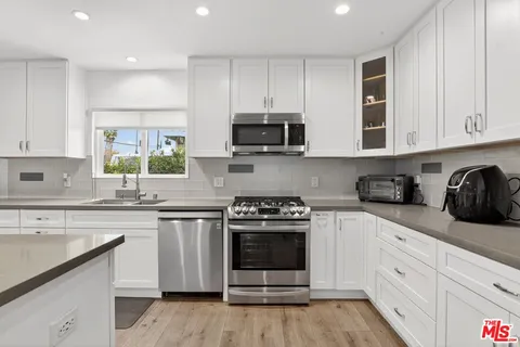 a kitchen with stainless steel appliances granite countertop a stove a sink and a microwave