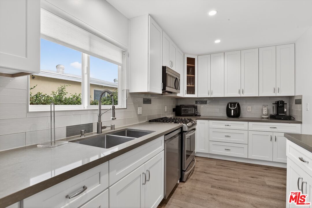 6565 Randi Avenue Woodland Hills, CA 91303 - Photo 10 of 25 a kitchen with stainless steel appliances granite countertop a sink a stove and cabinets