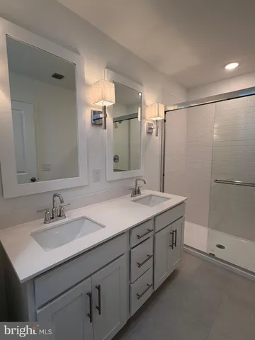 a bathroom with a sink double vanity granite tub shower and a mirror
