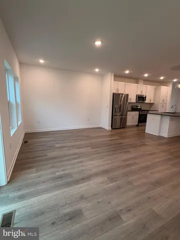 a view of a kitchen with kitchen island a sink wooden floor and a living room view