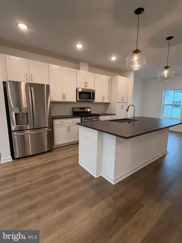 a kitchen with stainless steel appliances granite countertop a sink a stove a refrigerator and island with wooden floor