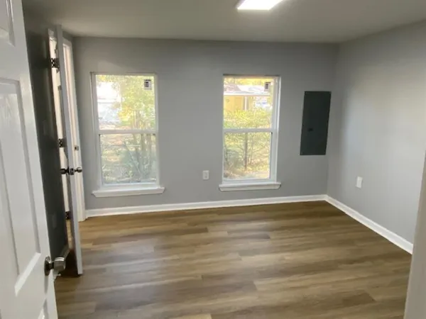 a view of an empty room with wooden floor and a window