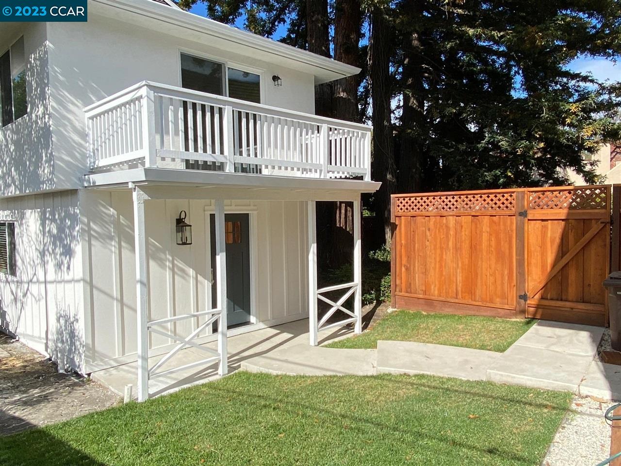 a view of a house with backyard and wooden fence