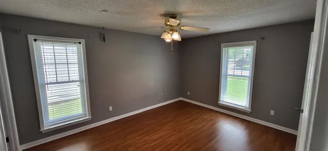 an empty room with wooden floor closet and windows