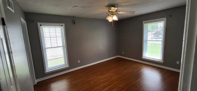 an empty room with wooden floor and windows