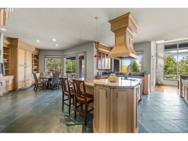 a open kitchen with stainless steel appliances granite countertop a kitchen island a stove a table and chairs