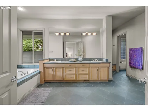 a bathroom with a granite countertop tub double vanity sink and mirror
