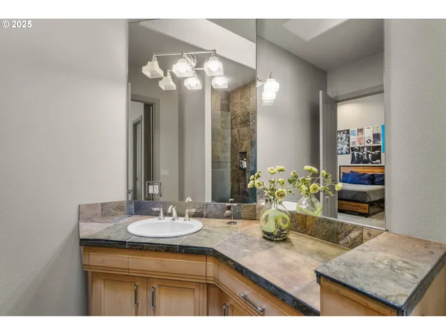 a bathroom with a granite countertop sink a large mirror and a white walls