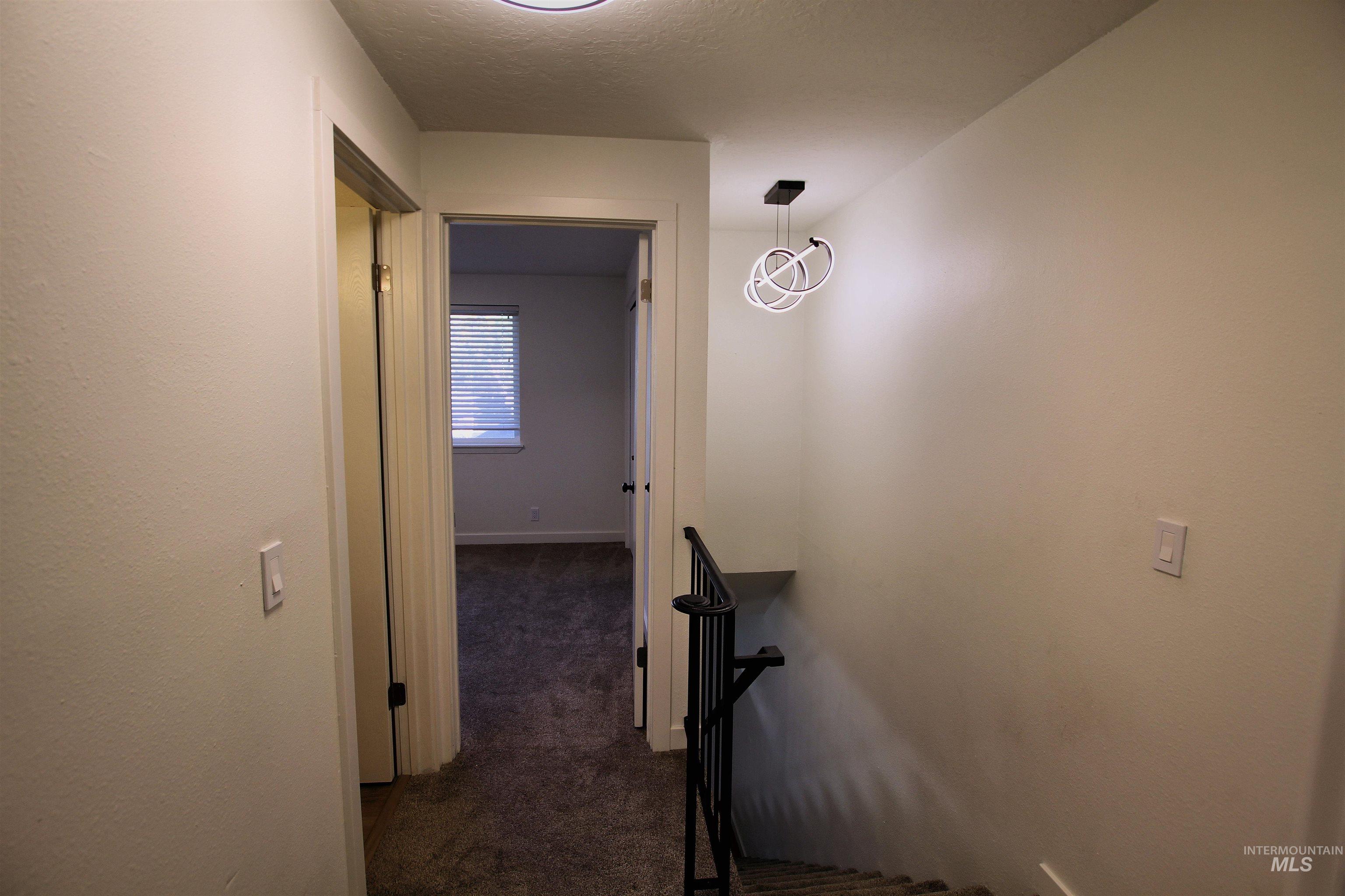 8405 West Rifleman Street Boise, ID 83704 - Photo 11 of 11 Corridor featuring dark colored carpet, a textured ceiling, and an upstairs landing