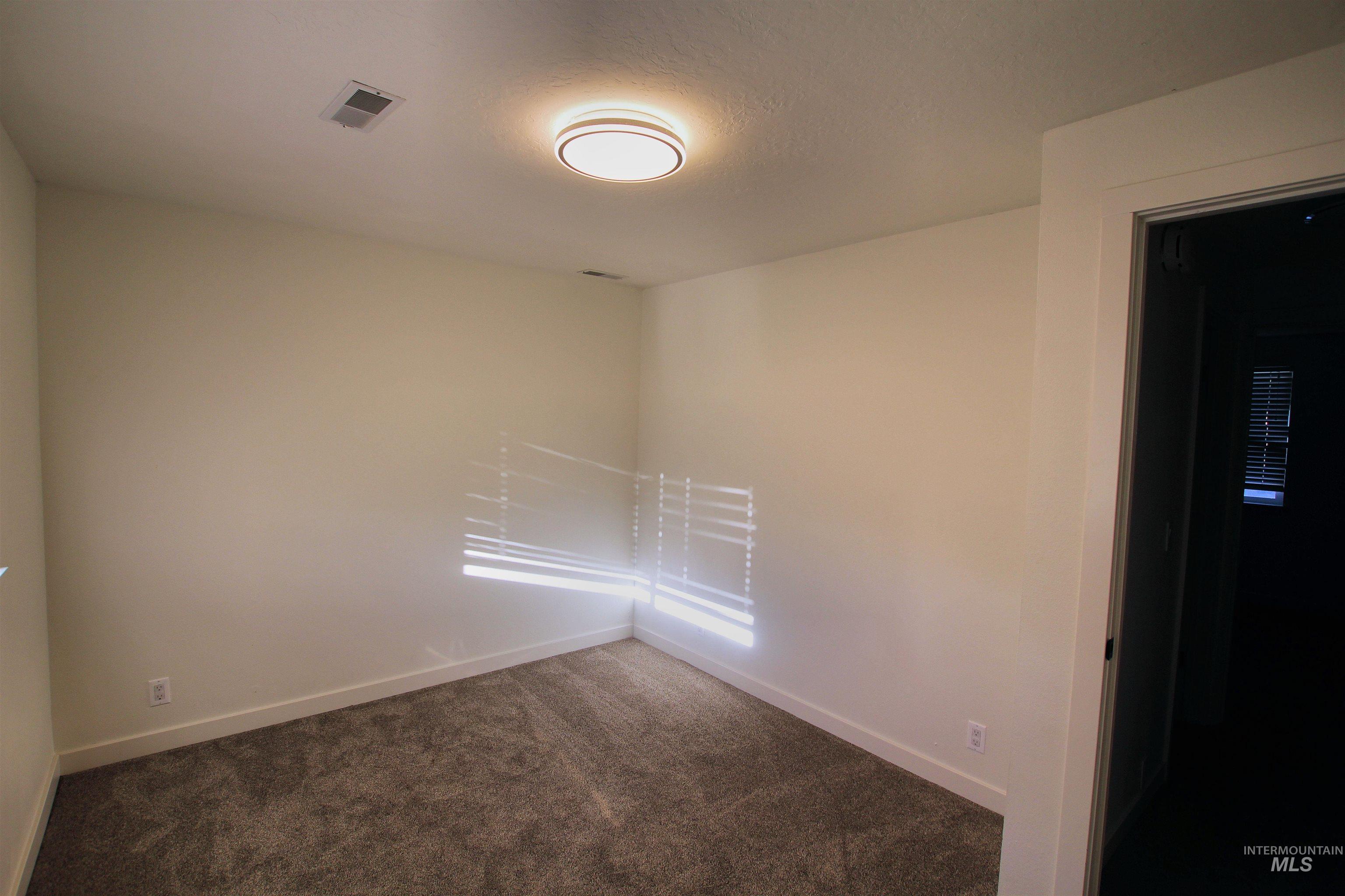 8405 West Rifleman Street Boise, ID 83704 - Photo 5 of 11 Unfurnished room featuring dark colored carpet and a textured ceiling