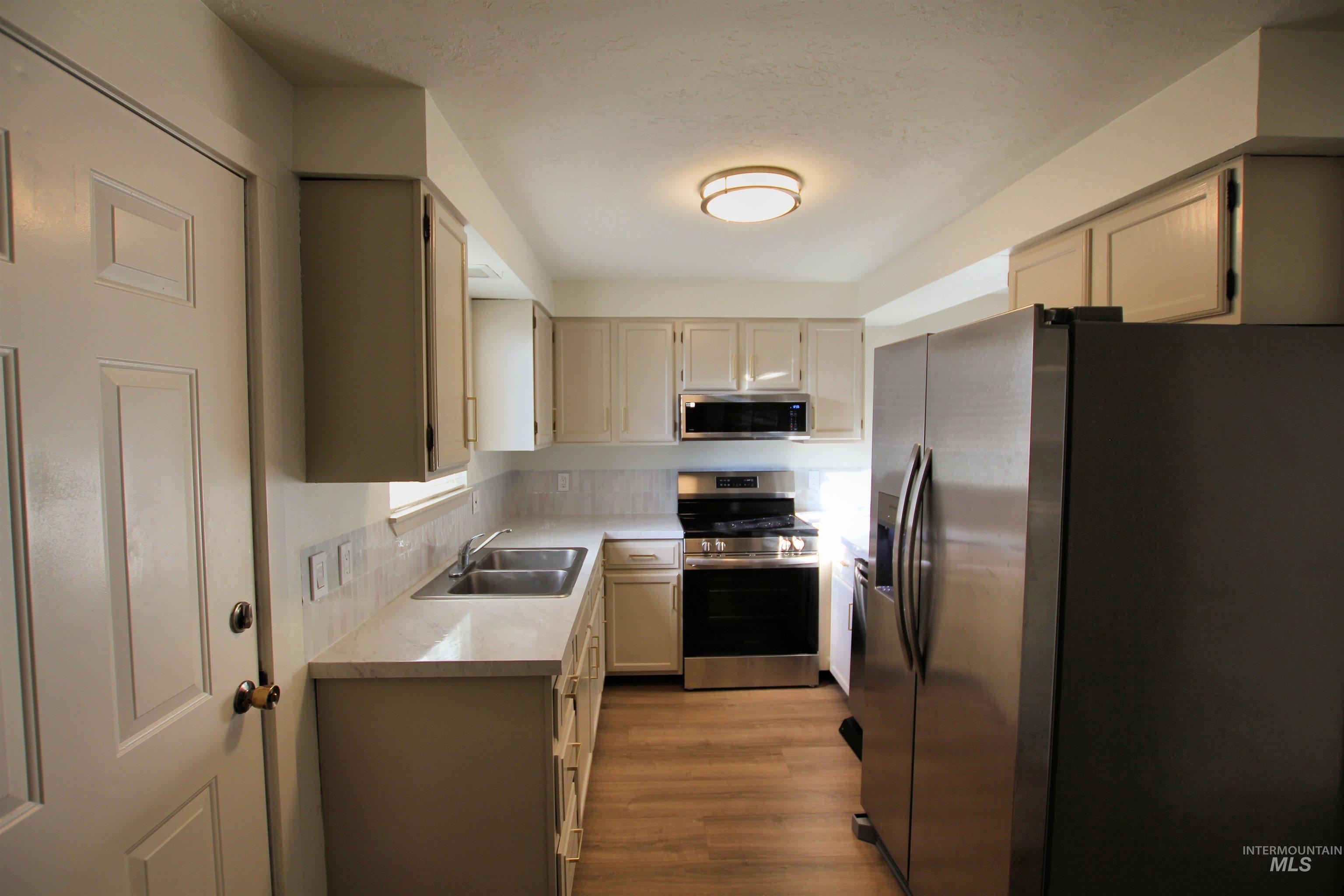 8405 West Rifleman Street Boise, ID 83704 - Photo 7 of 11 Kitchen with stainless steel appliances, light countertops, light wood-style floors, and backsplash