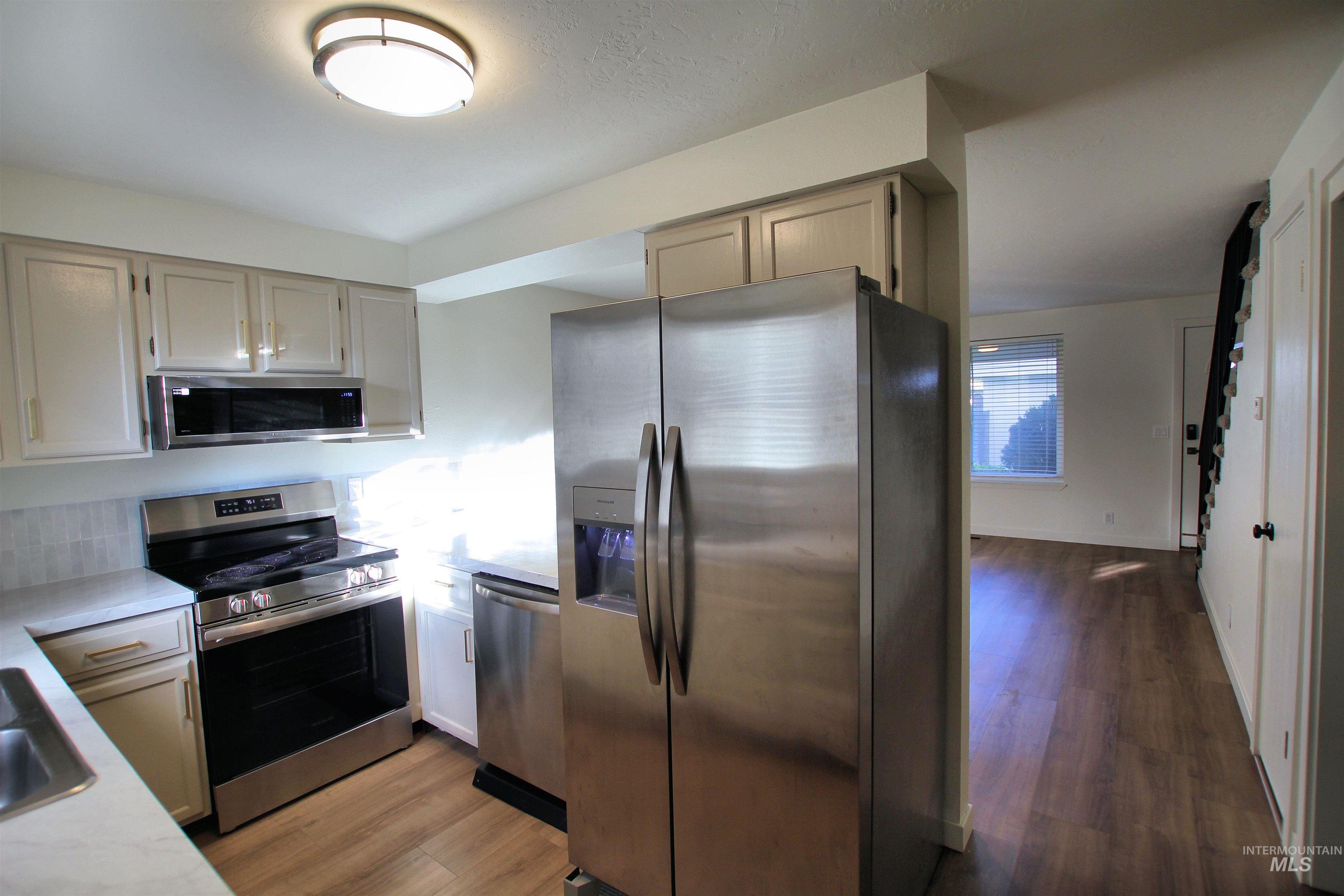 8405 West Rifleman Street Boise, ID 83704 - Photo 8 of 11 Kitchen featuring appliances with stainless steel finishes, dark wood-type flooring, and light stone countertops