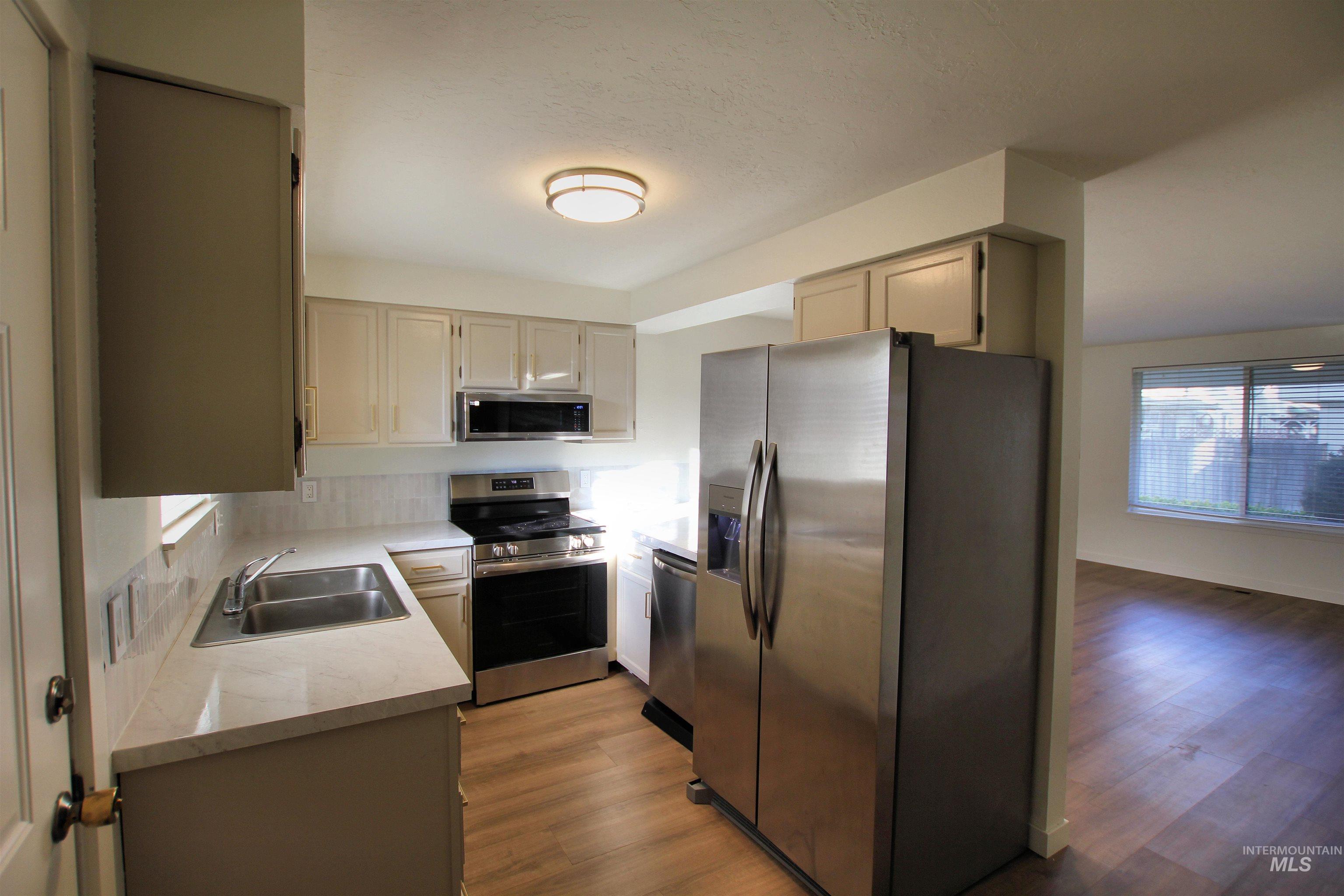 8405 West Rifleman Street Boise, ID 83704 - Photo 9 of 11 Kitchen featuring stainless steel appliances, light wood-style flooring, and decorative backsplash
