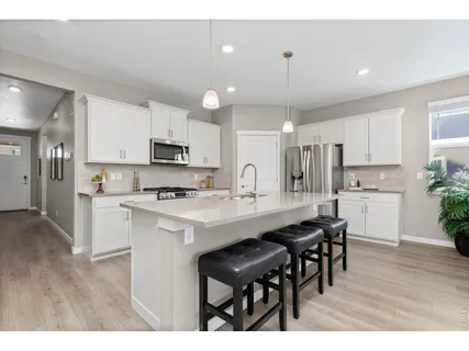 a kitchen with kitchen island granite countertop a sink cabinets and wooden floor