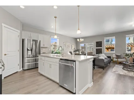 a kitchen with stainless steel appliances kitchen island granite countertop a refrigerator oven a sink dishwasher and white cabinets with wooden floor