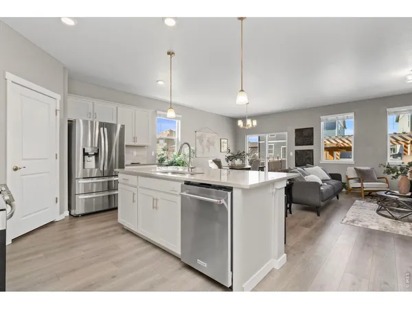 a kitchen with stainless steel appliances kitchen island granite countertop a refrigerator oven a sink dishwasher and white cabinets with wooden floor